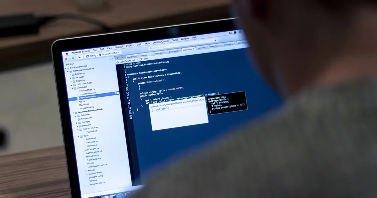 A developer looks at code in an editor on a laptop screen in a dim room
